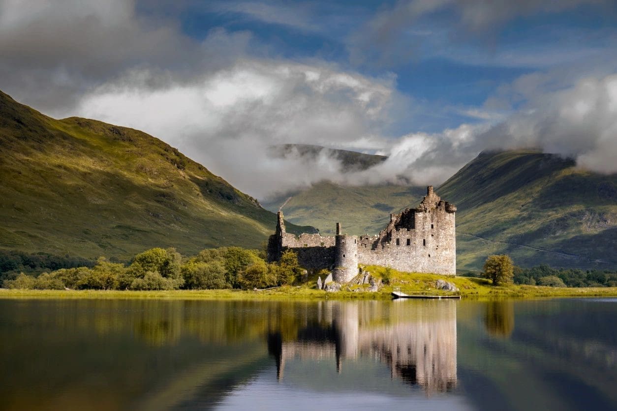 A castle sits on the shore of a lake.