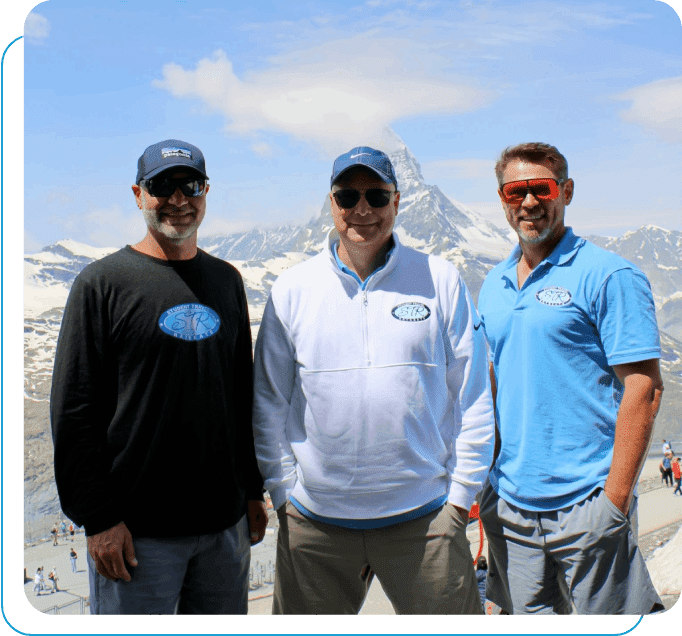 Three men standing in front of a mountain.