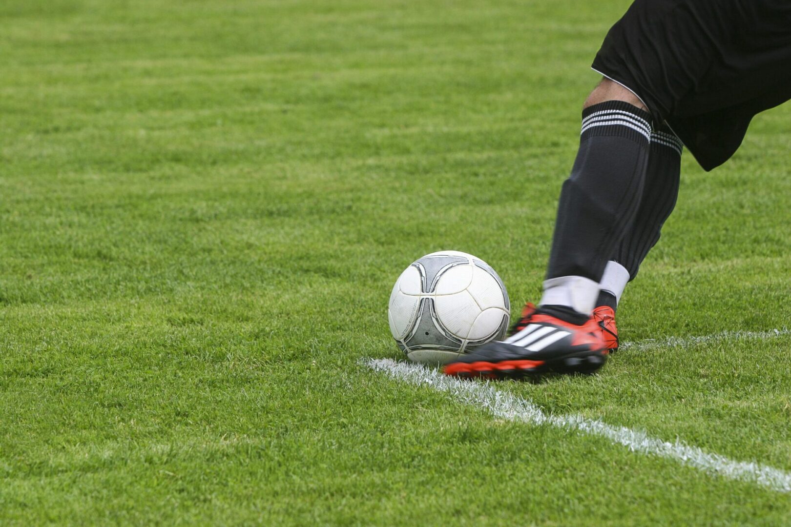 A soccer ball is on the ground near a line.